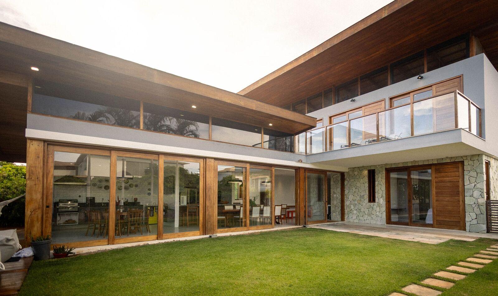 Contemporary wood, glass and stone home with a lawn
